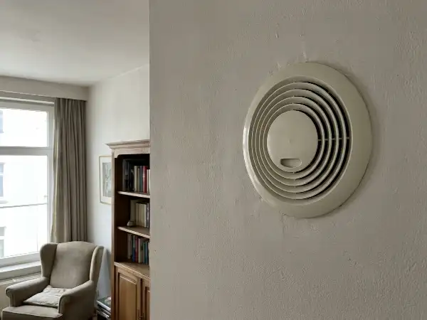 Decentraal ventilatietoestel hoog in de muur van een woonkamer